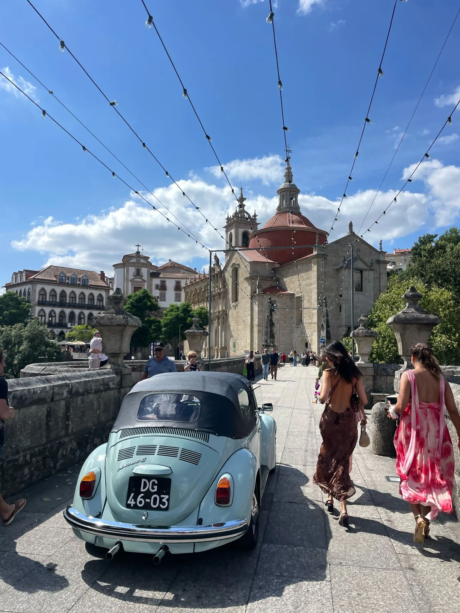 A vintage mint VW Beetle on a Portuguese square strung with festoon lights