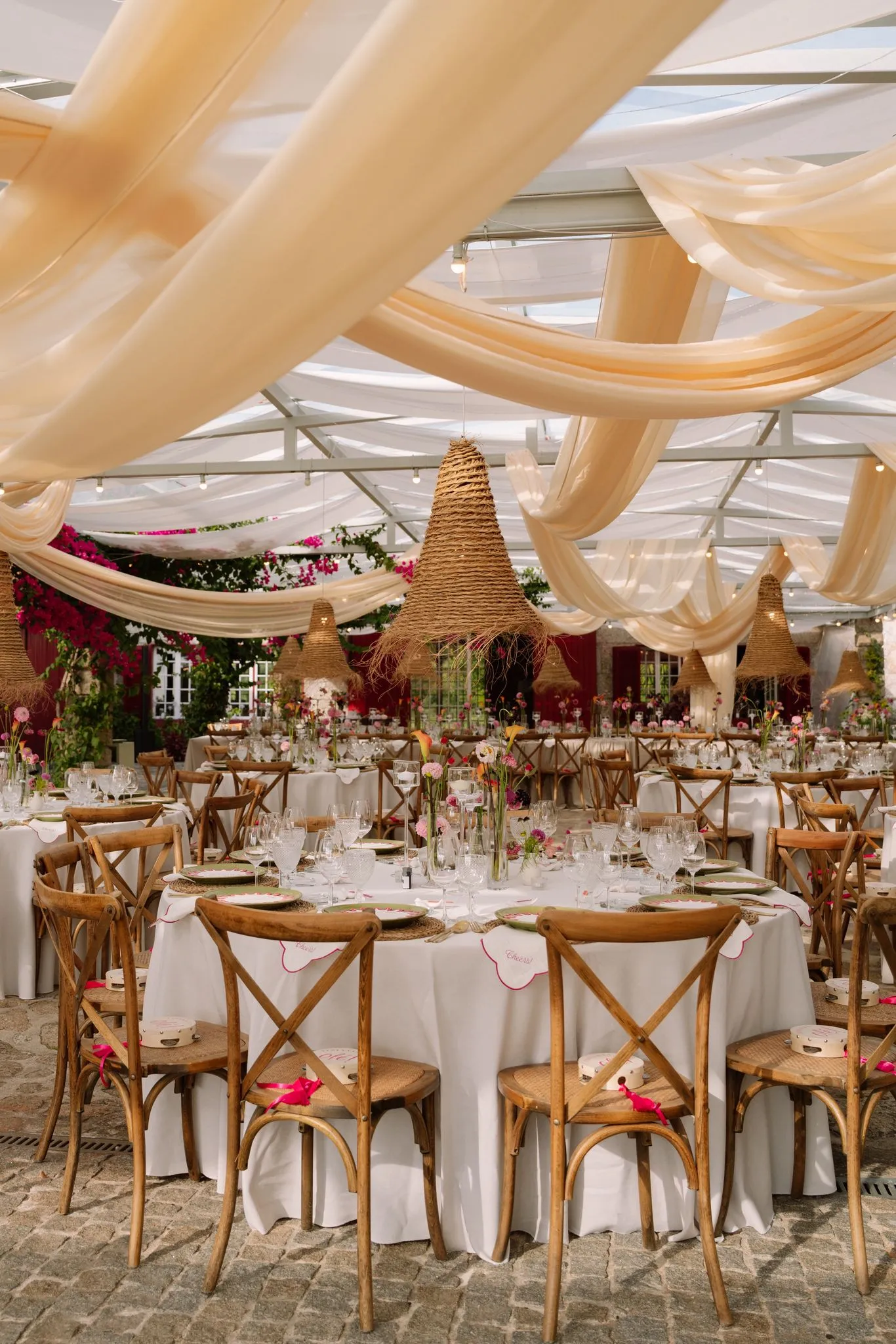 An elegant outdoor reception under draped fabric and woven lamps