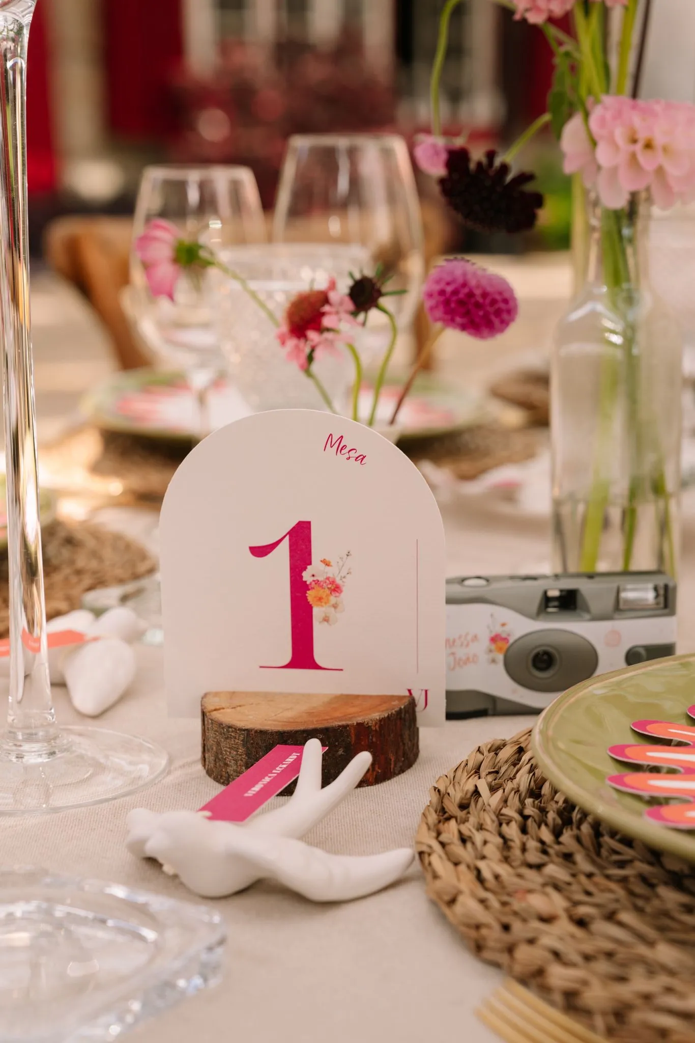 An arched table number in hot pink beside a disposable camera