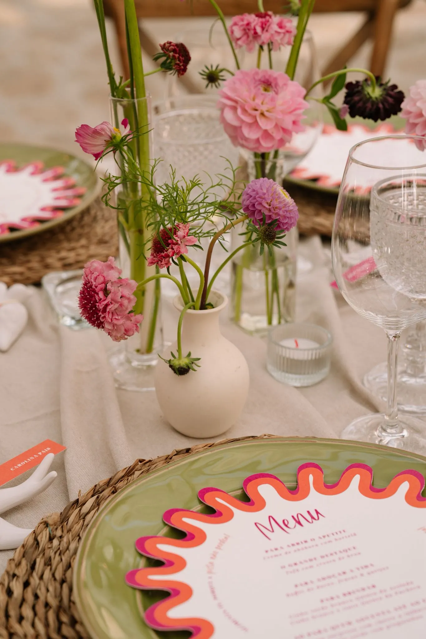 A styled place setting with a wavy menu and pink blooms