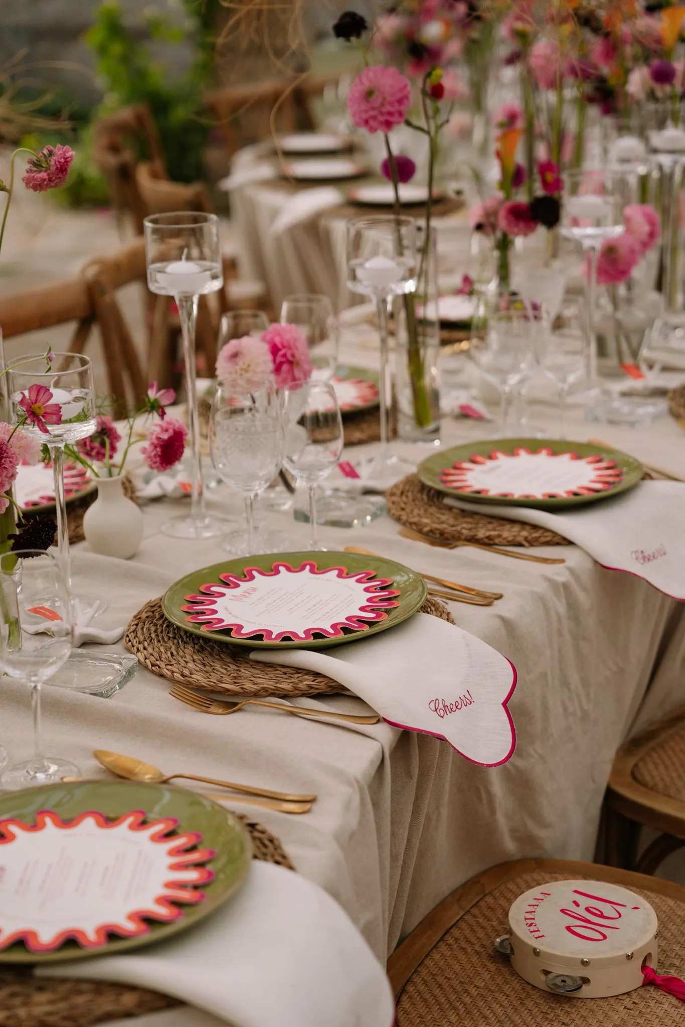 A long banquet table with green wavy plates and embroidered napkins