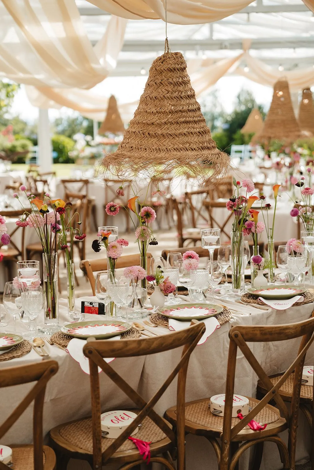 A tented reception with raffia lamps and wildflower centerpieces